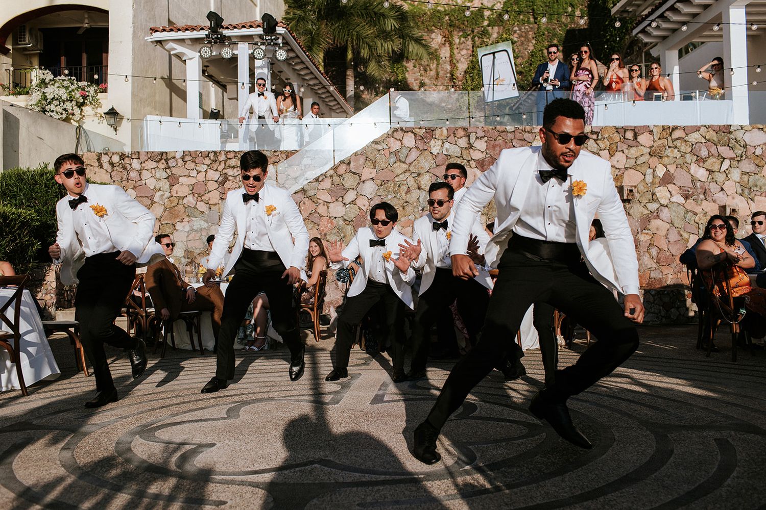 Groomsmen in white tuxedos perform a fun dance during a luxury wedding reception in Puerto Vallarta, captured by José Carrillo.