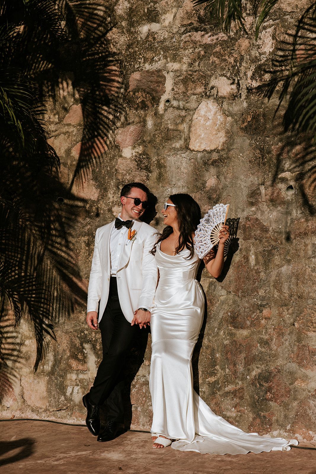 Bride and groom in elegant white attire share a candid sunset moment in Puerto Vallarta, captured by luxury photographer José Carrillo.