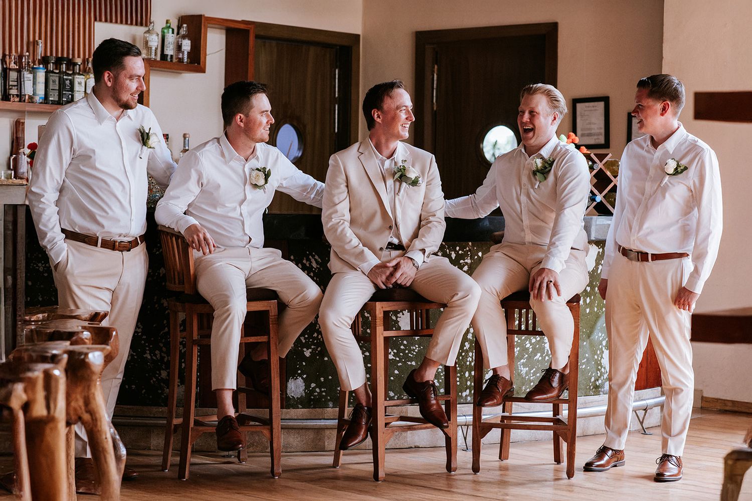 Groom and groomsmen share laughter in a tropical lounge before the ceremony in Puerto Vallarta, by José Carrillo Photography.