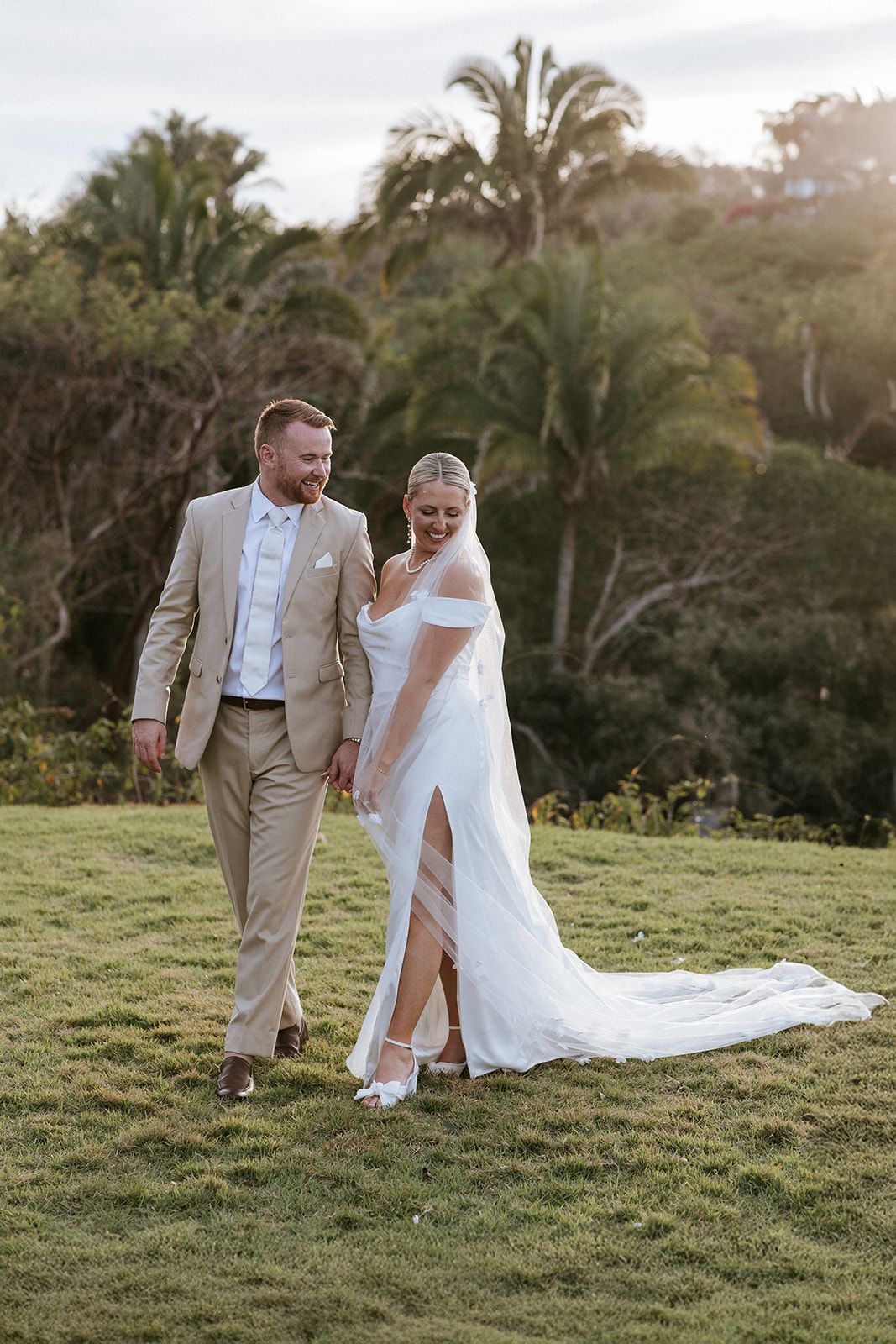 Bride and groom walking hand in hand through a lush garden in Puerto Vallarta, captured naturally by José Carrillo Photography.