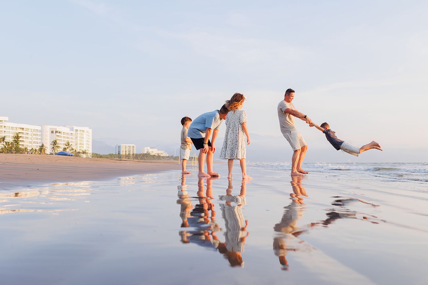 Family playing together on the shoreline during a natural beach photo session in Puerto Vallarta