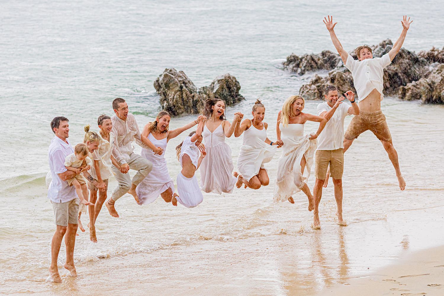 Extended family jumping together at the water’s edge during a Puerto Vallarta beach photo session