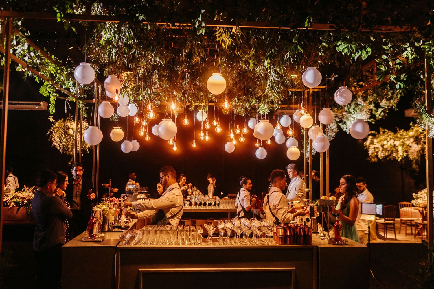 Outdoor wedding reception with hanging lights and tropical greenery
