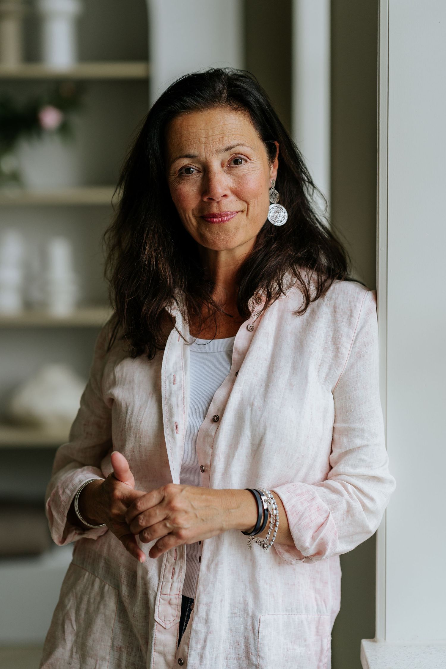 Business dame in Ede staat bij het raam en kijkt met een klein lachje in de camera