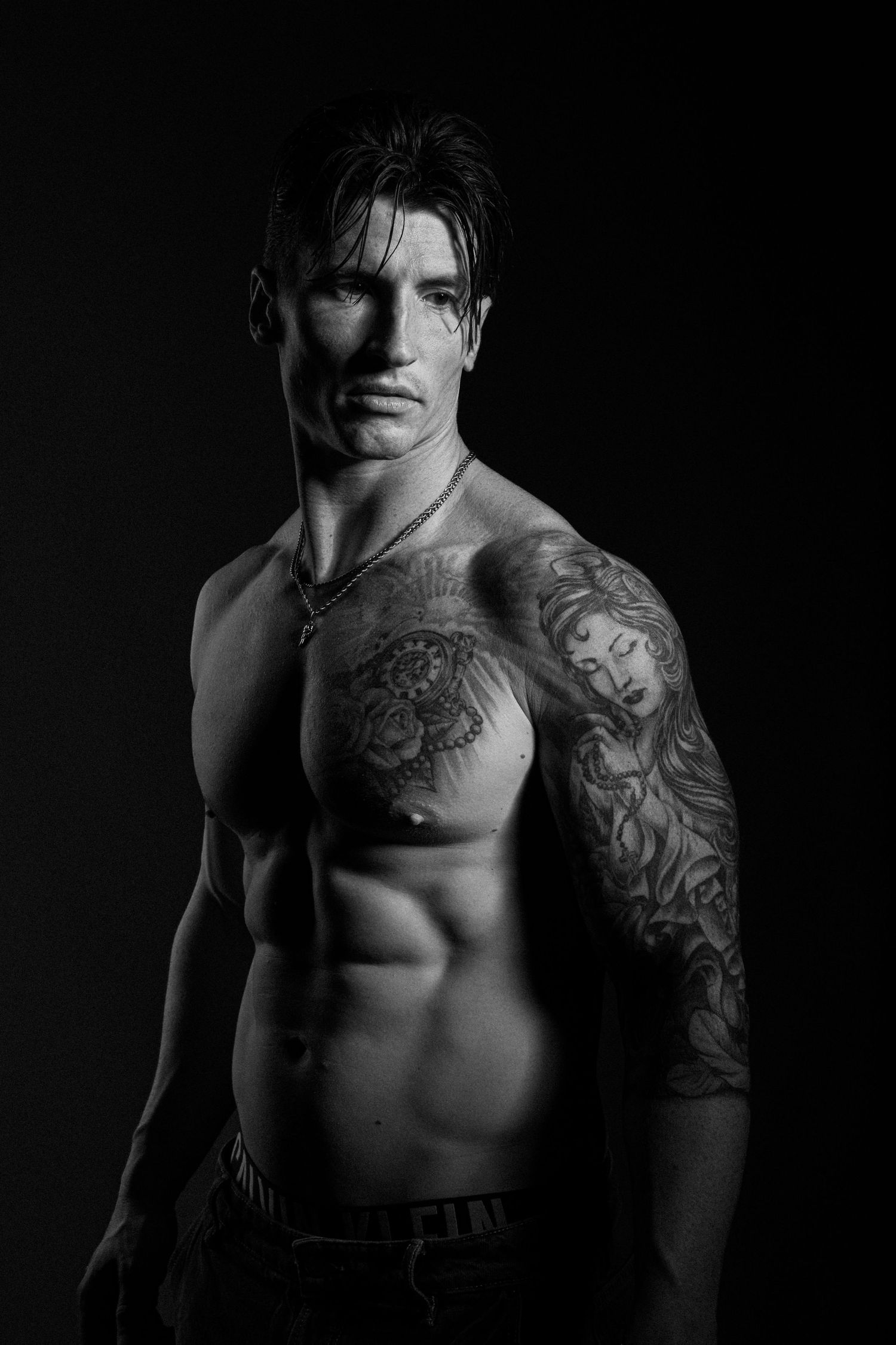 Low-key studio portrait of a tattooed male fitness model photographed in Sydney.
