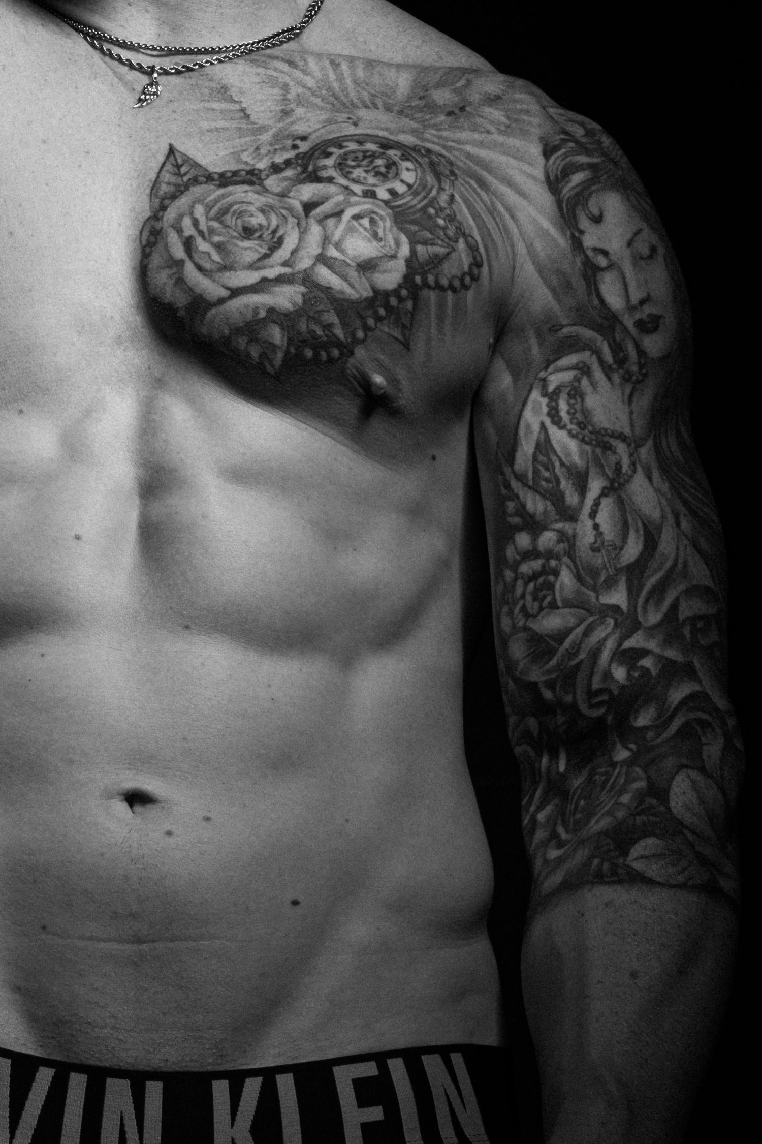 Black and white close-up portrait of a tattooed male model showcasing detailed sleeve tattoos and physique in a Sydney studio.