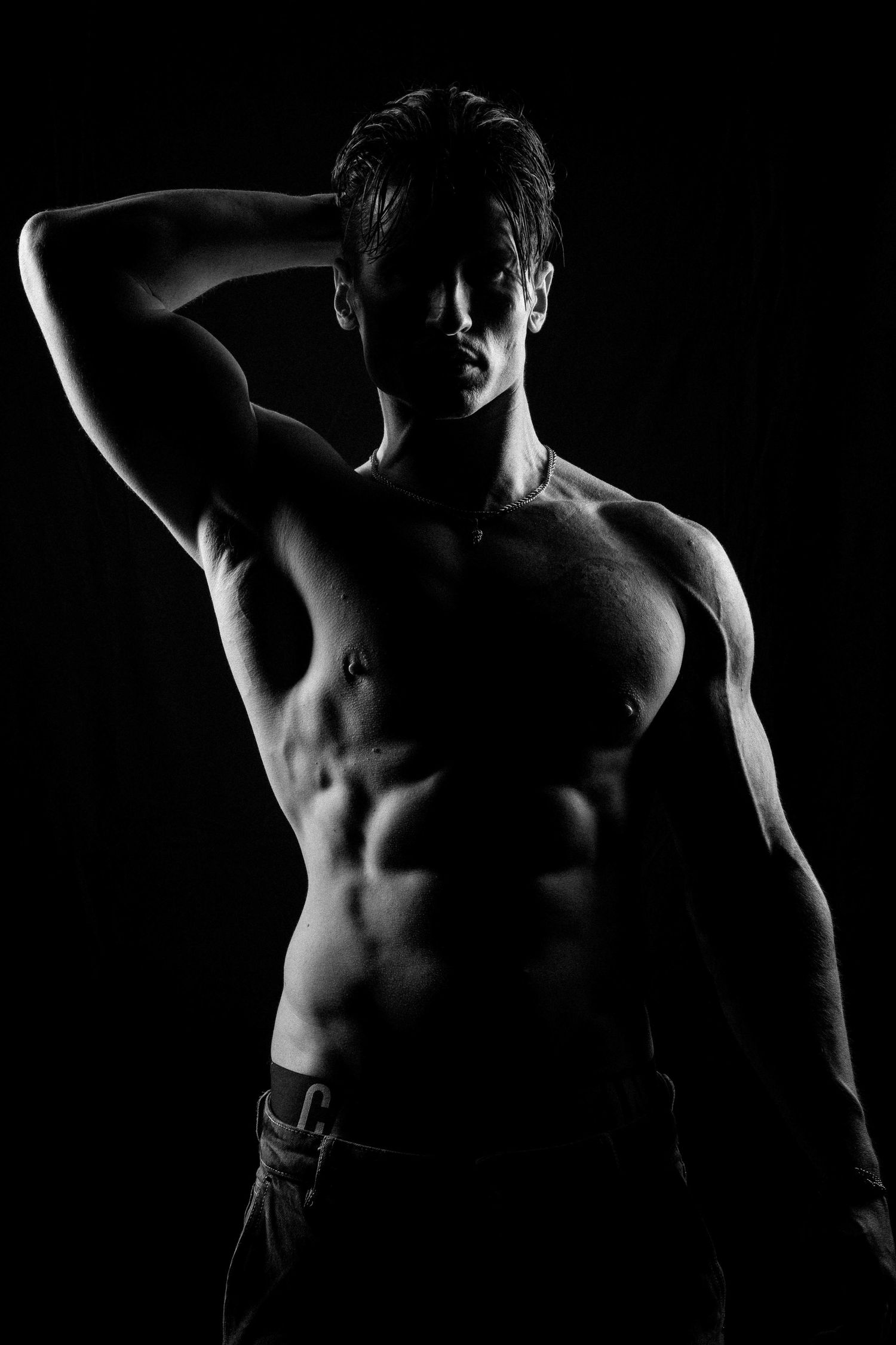 Silhouette portrait of a tattooed male fitness model using dramatic studio lighting in Sydney.