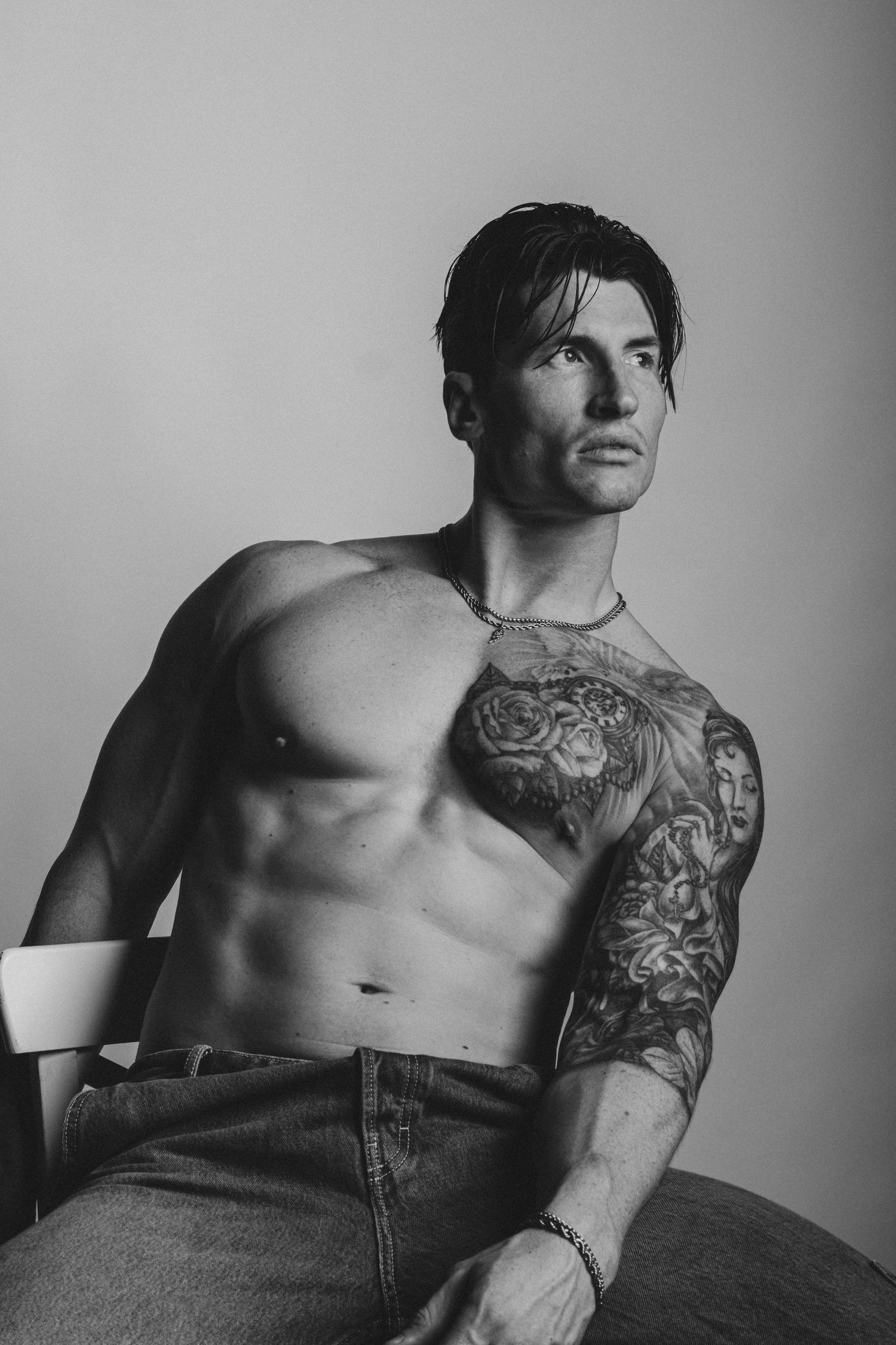 Editorial portrait of a tattooed male fitness model seated in a Sydney photography studio.