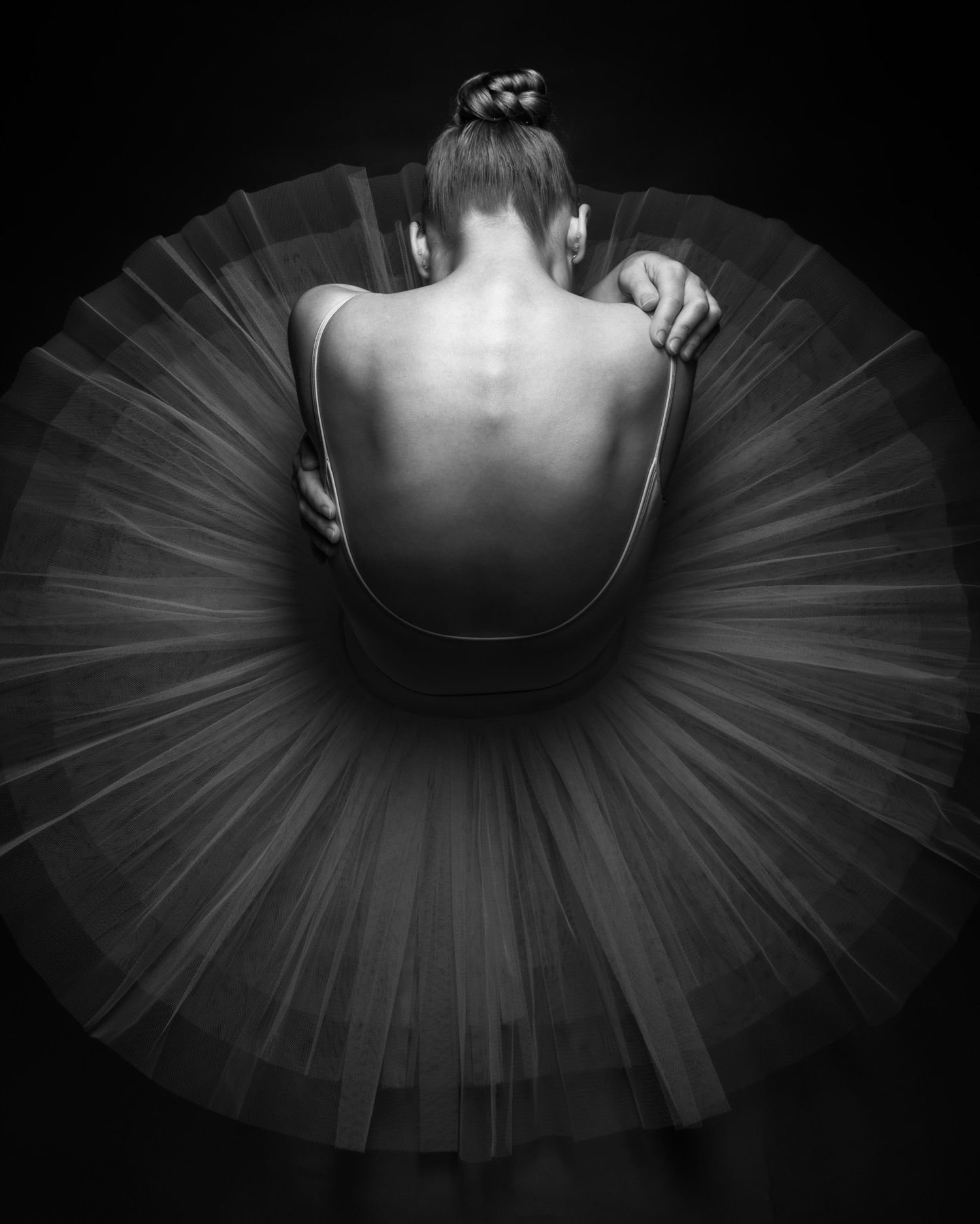 Black and white fine art portrait of a ballerina viewed from above, with a flowing tulle skirt tutu creating a circular shape.
