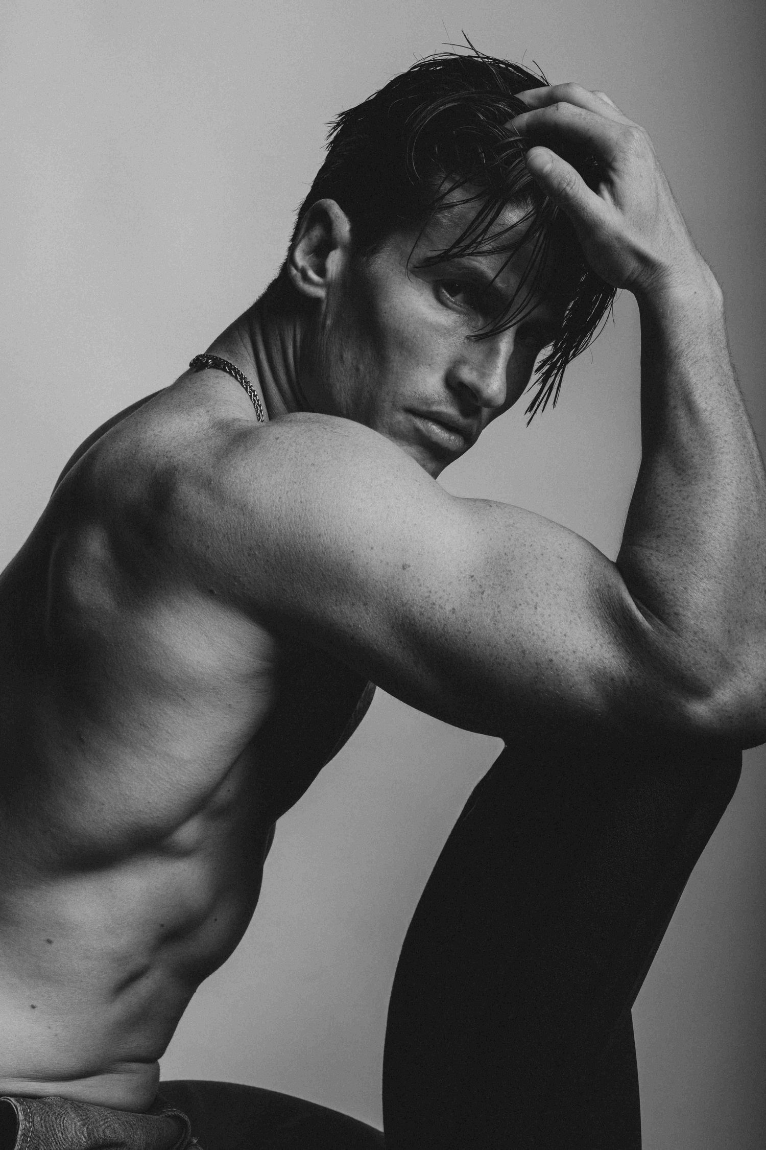 Black and white portrait of a tattooed male model with an intense expression in a Sydney studio.