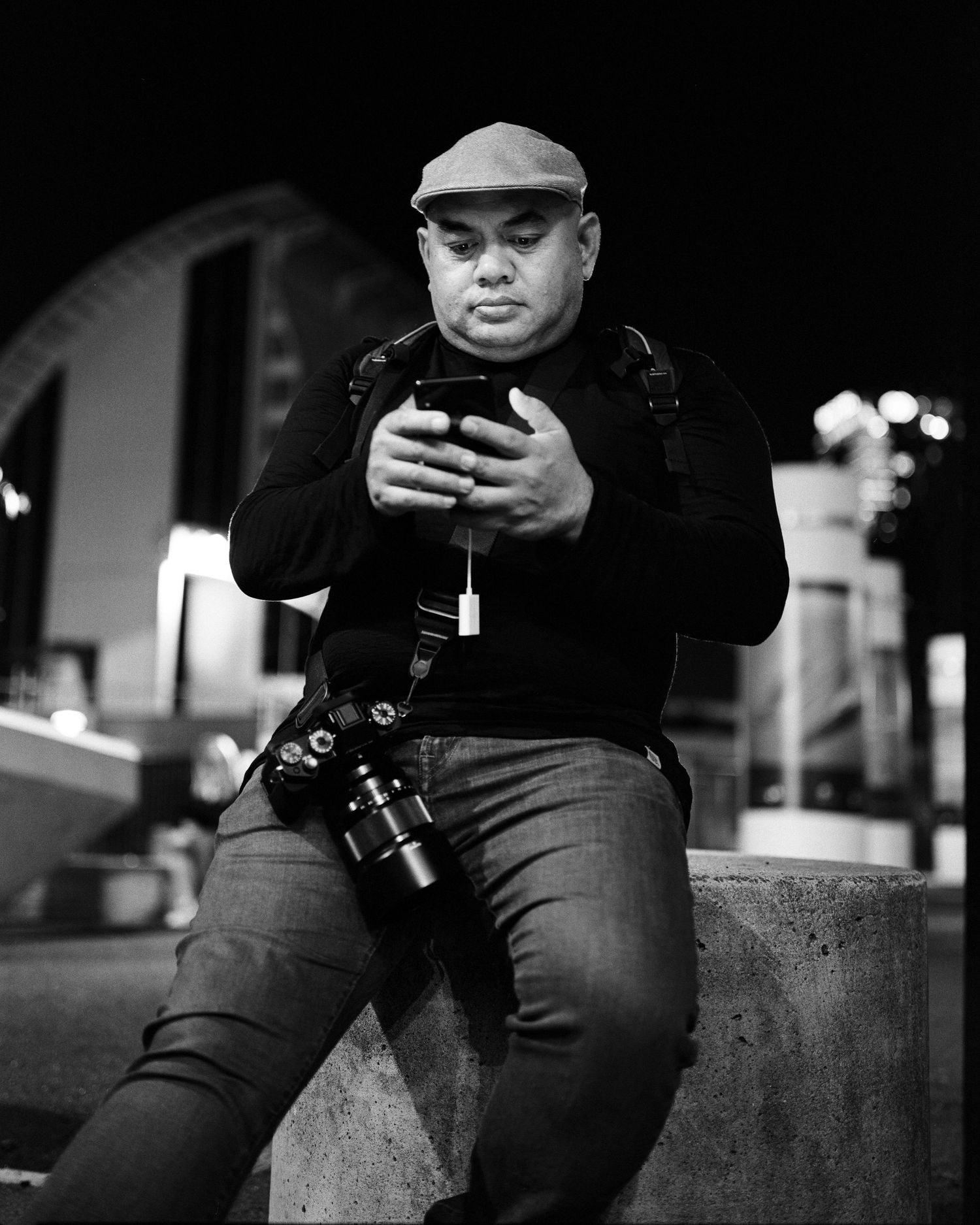 Portrait of Sydney photographer Lee checking camera settings during a night shoot in black and white.