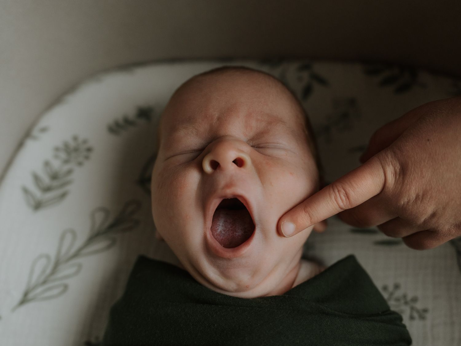 A collage of six intimate newborn baby photos showing yawning, sleeping, and close-up details in soft lighting.