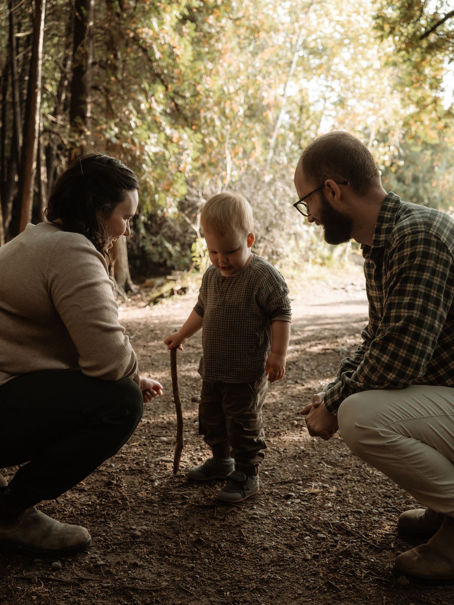 A family explores a wooded trail together on an autumn afternoon as sunlight filters through the trees.