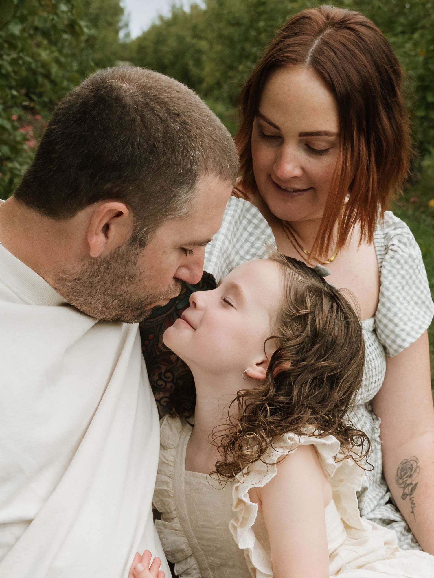 A family shares tender moments outdoors in a series of candid photos showing love and connection between parents and child.