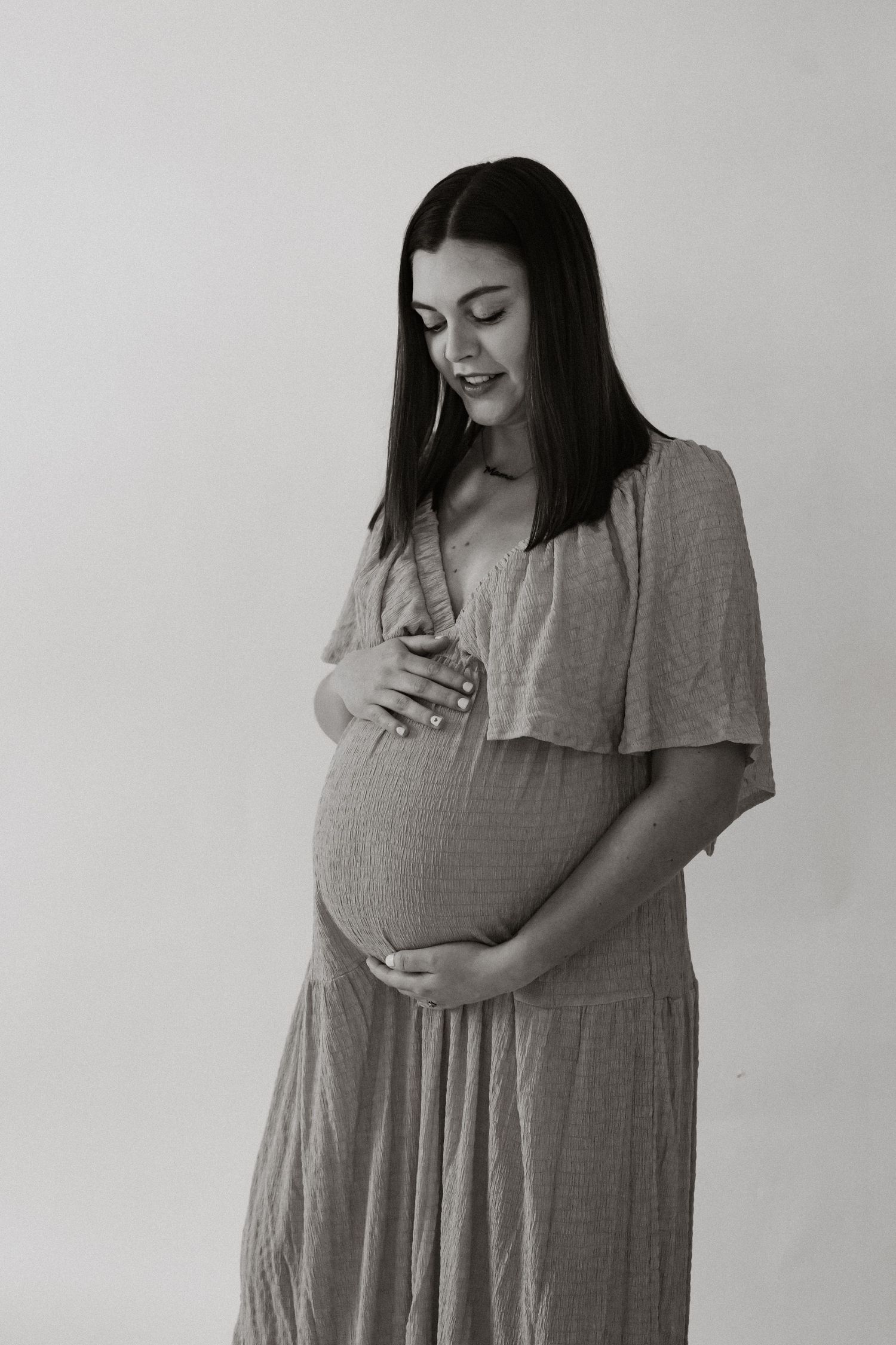 Black and white photo series showing a woman in a gray dress expressing joyful emotions against a plain background.