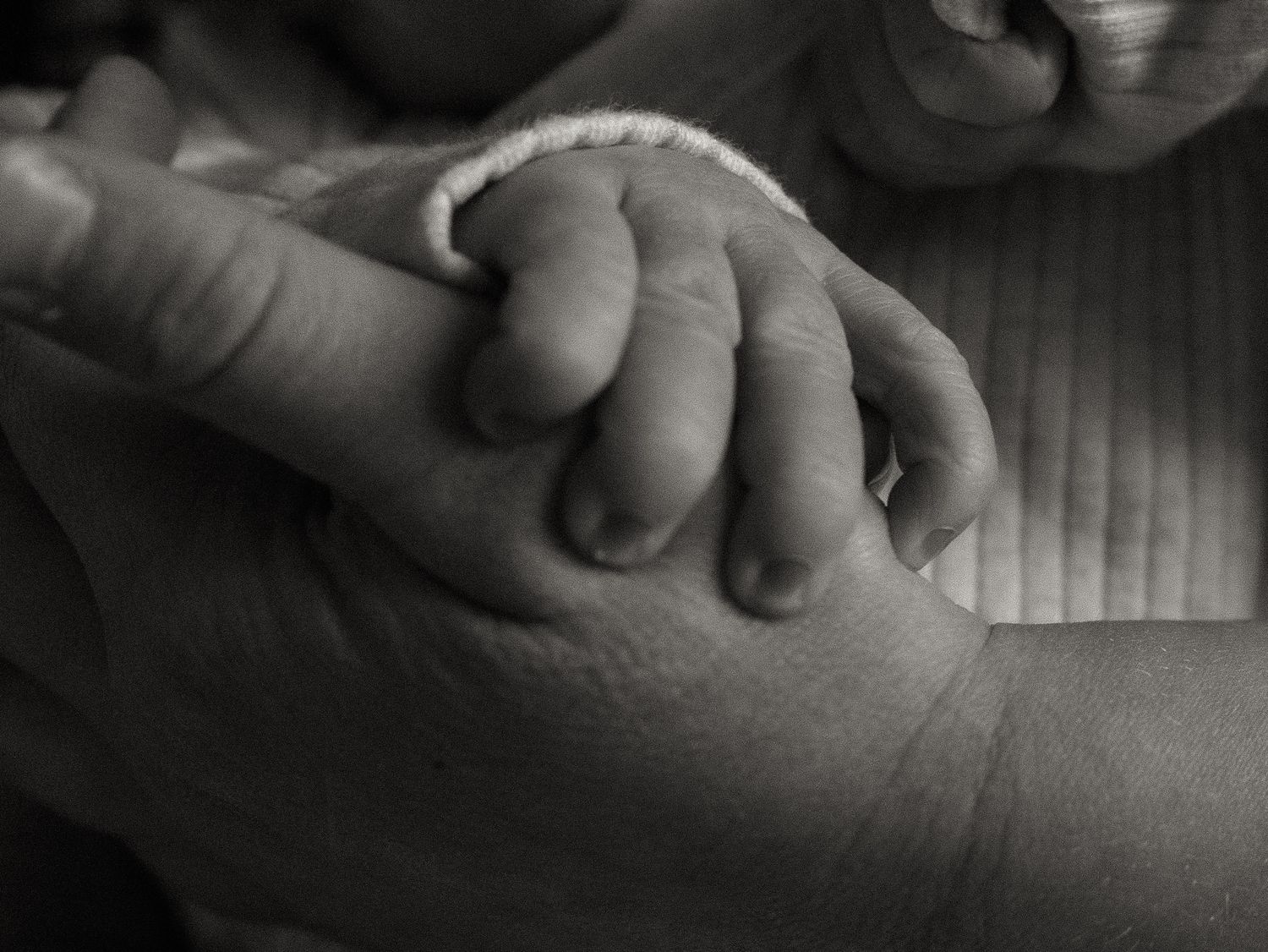 Close-up black and white image of hands gently holding and touching each other in a caring gesture.