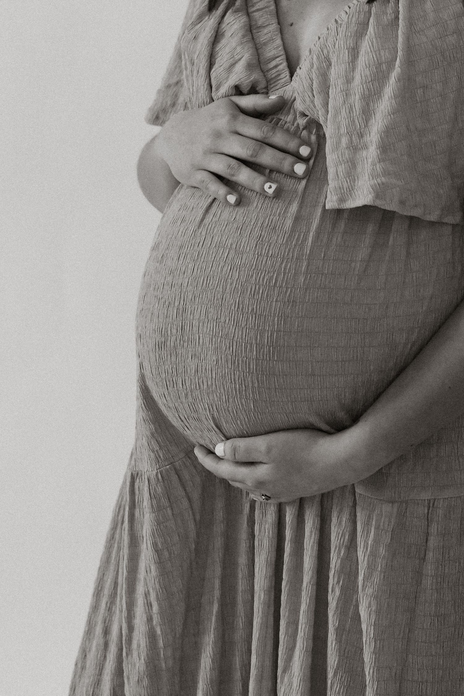 A series of monochromatic photos showing a pregnant belly growing progressively larger over time in a maternity dress.
