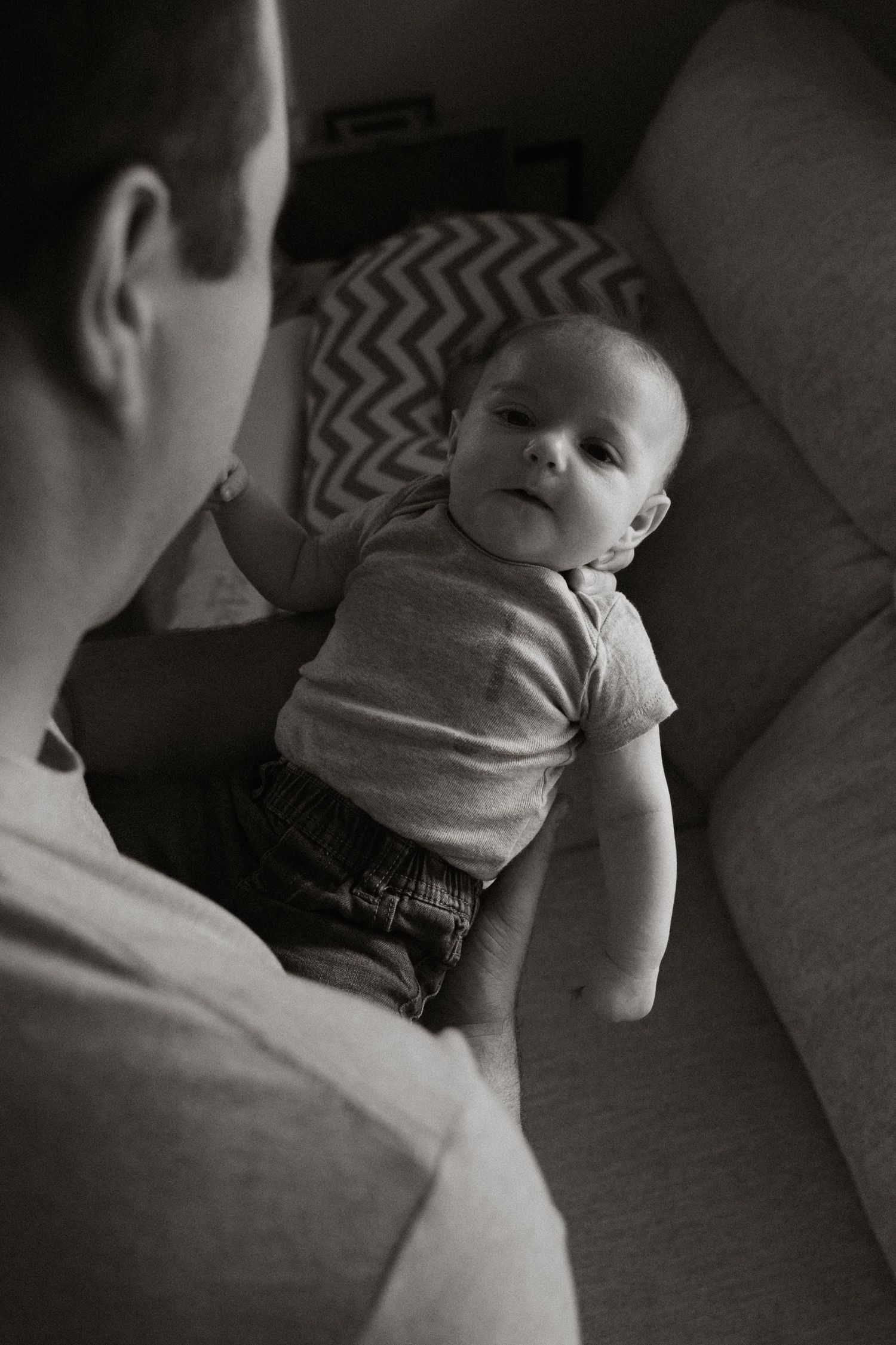 A series of black and white photos showing a baby lying on a patterned blanket while being comforted.