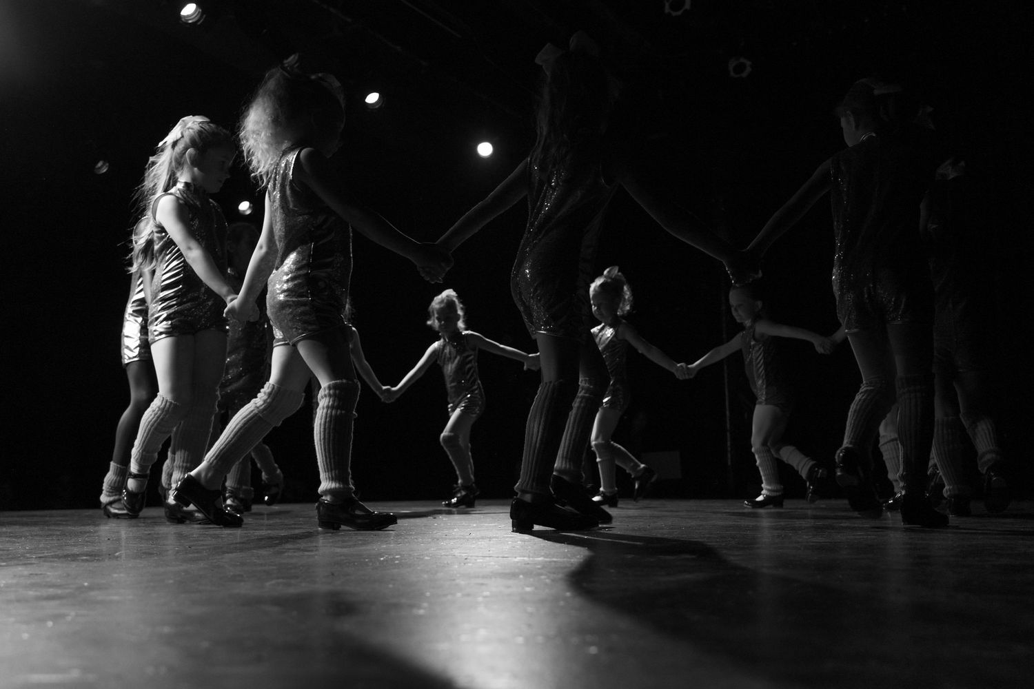 Black and white performance photos show dancers in dramatic poses on a dark stage under spotlights.
