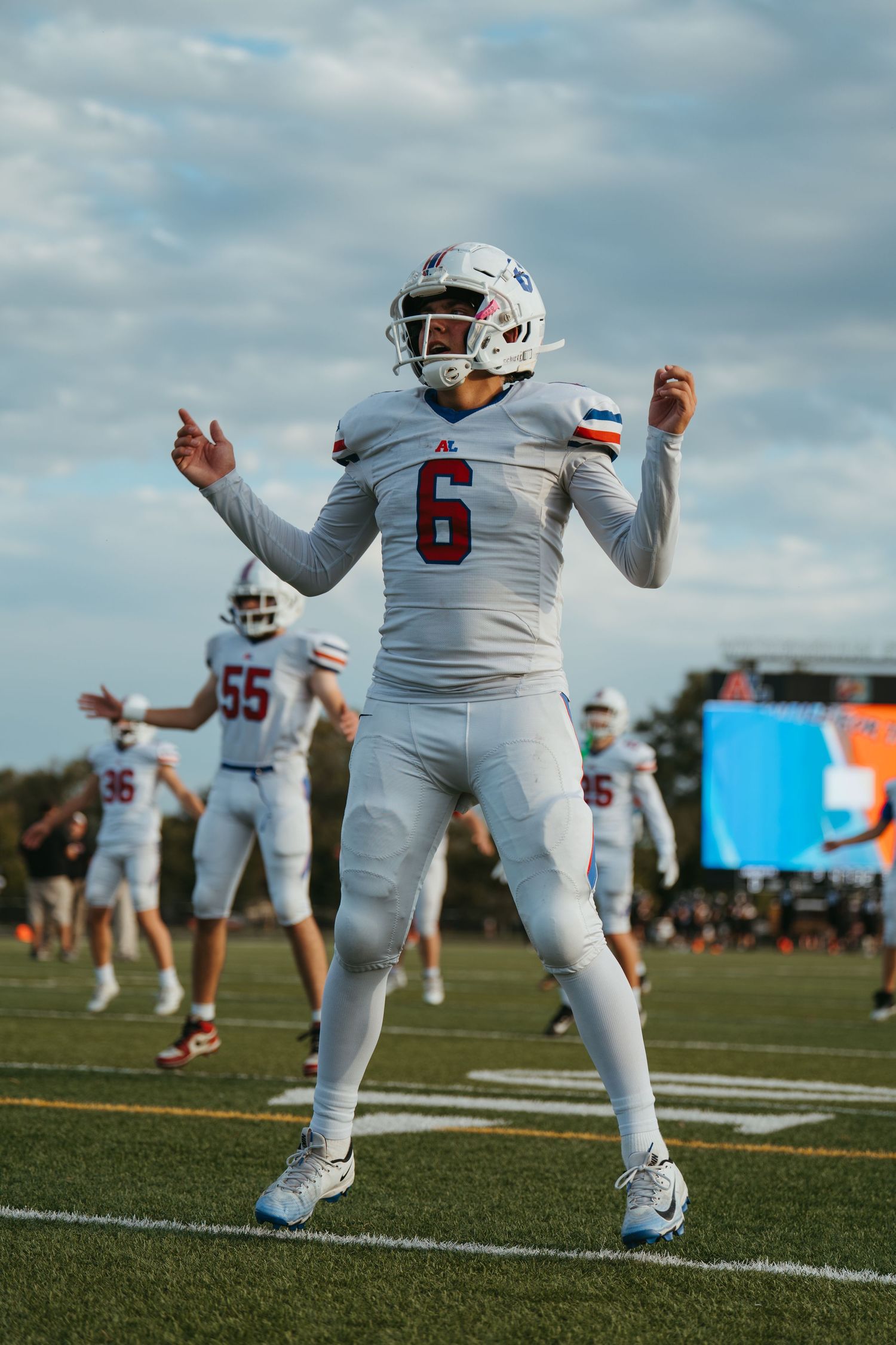 Football player wearing jersey number 6 in white uniform celebrates on field during a game.