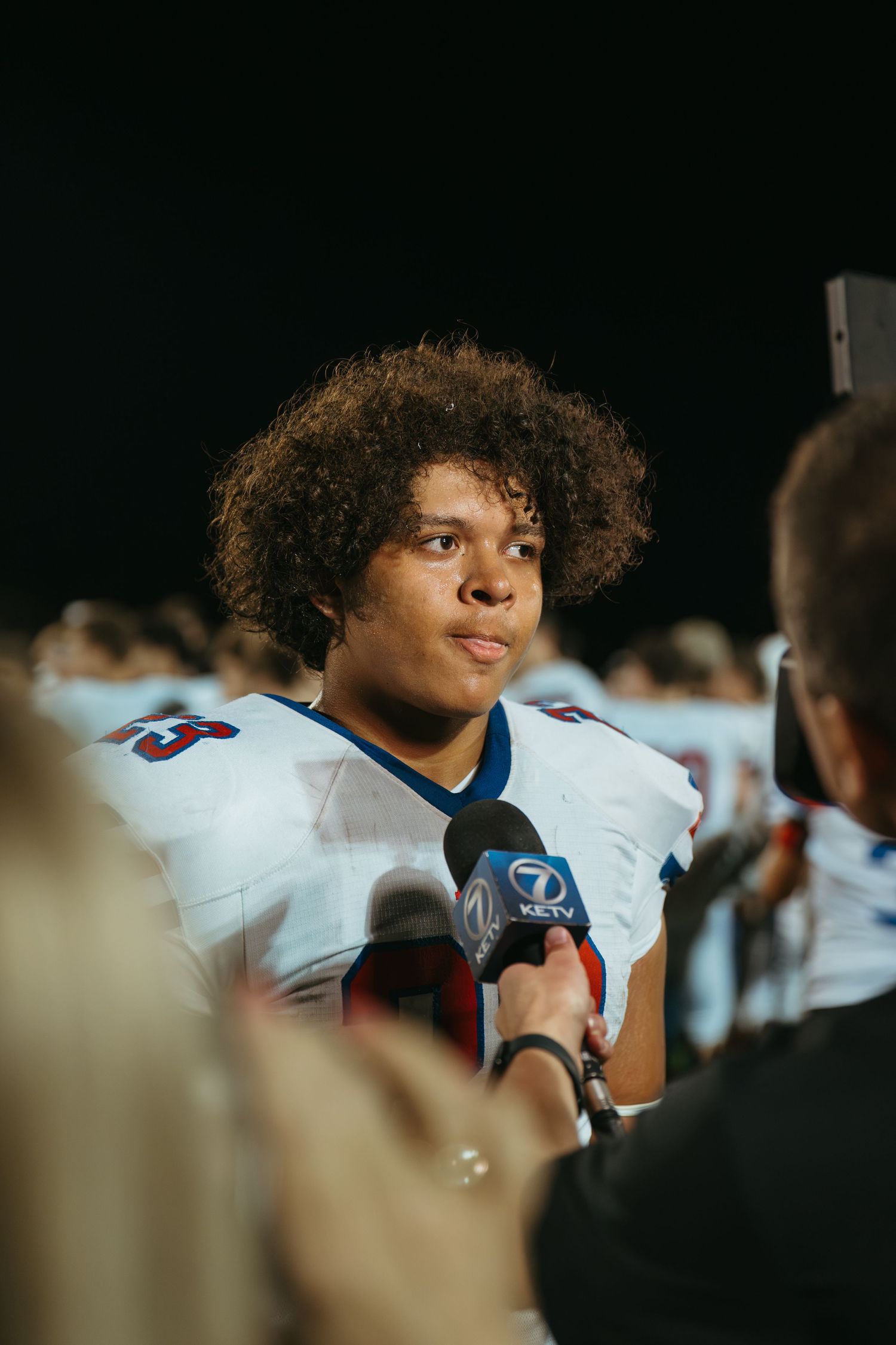 Football player in white jersey being interviewed by KETV Channel 7 reporter on field after game.