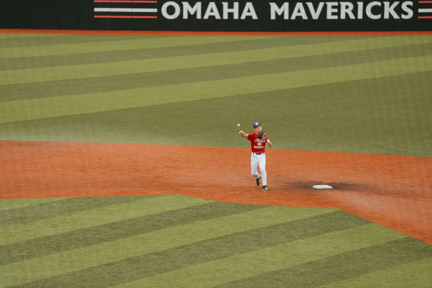 Omaha Mavericks baseball player throwing ball on field during game.
