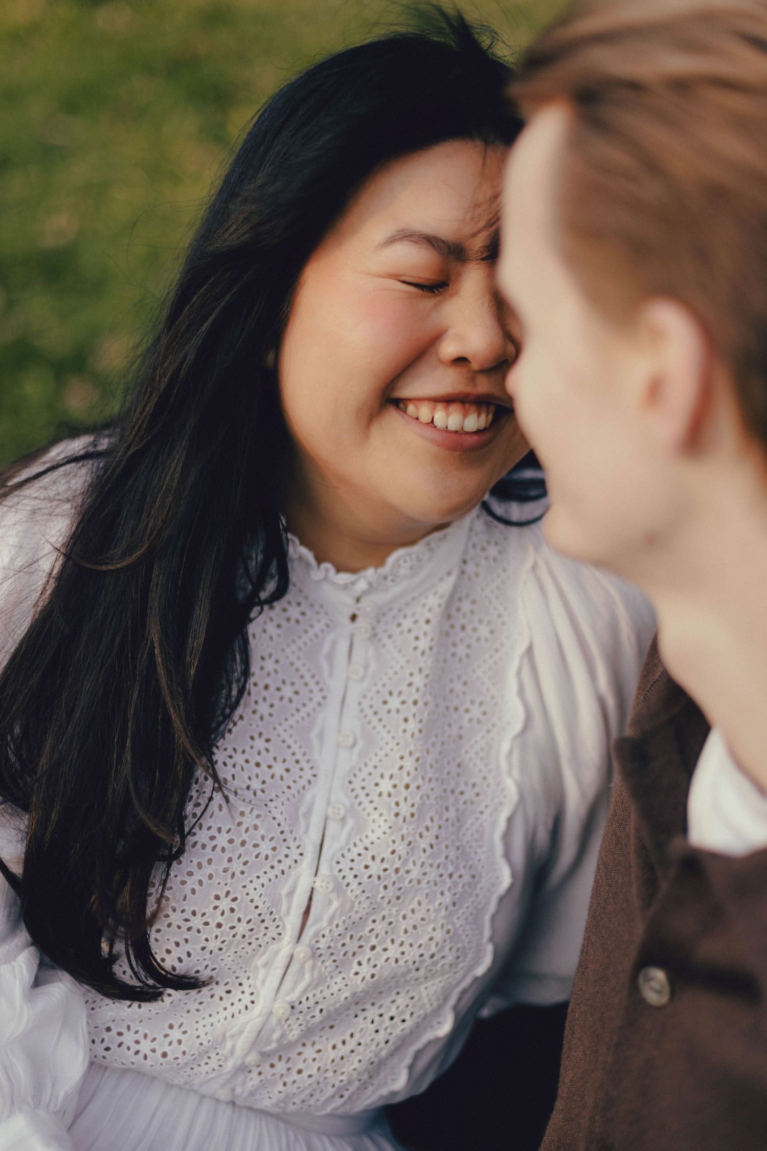 A tender moment captured between two people in white and brown clothing against a soft natural background.