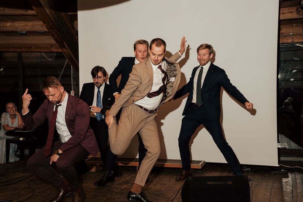 People dancing and having fun at what appears to be a wedding reception or party in a dimly lit venue.