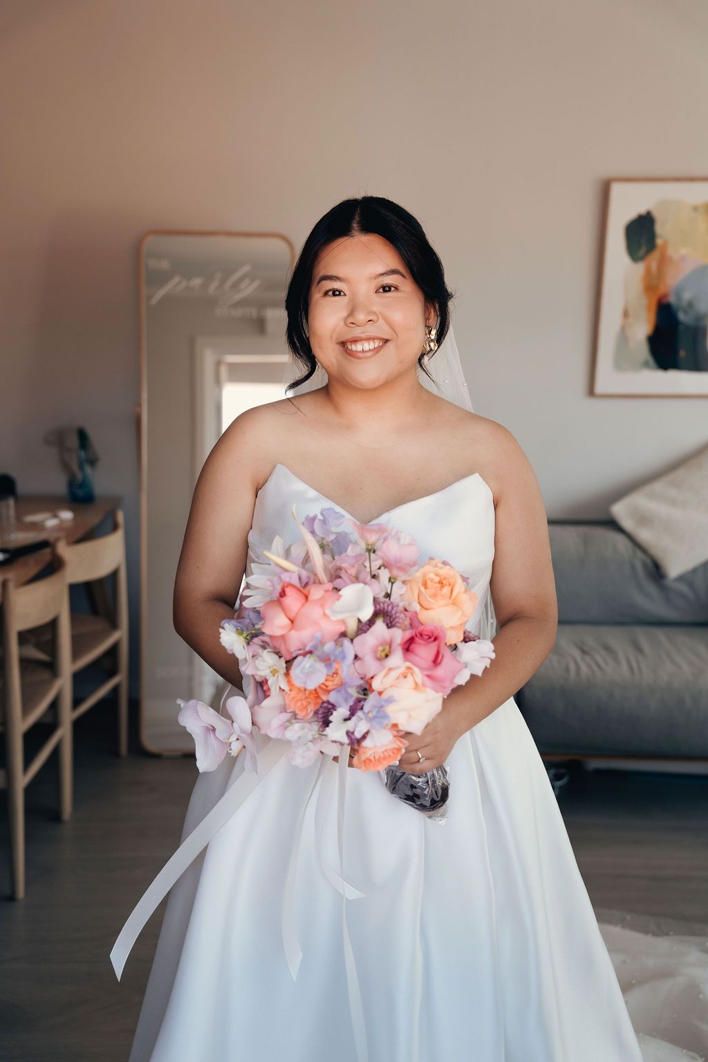 A close-up view of a white wedding dress featuring soft pink and lavender floral embellishments.