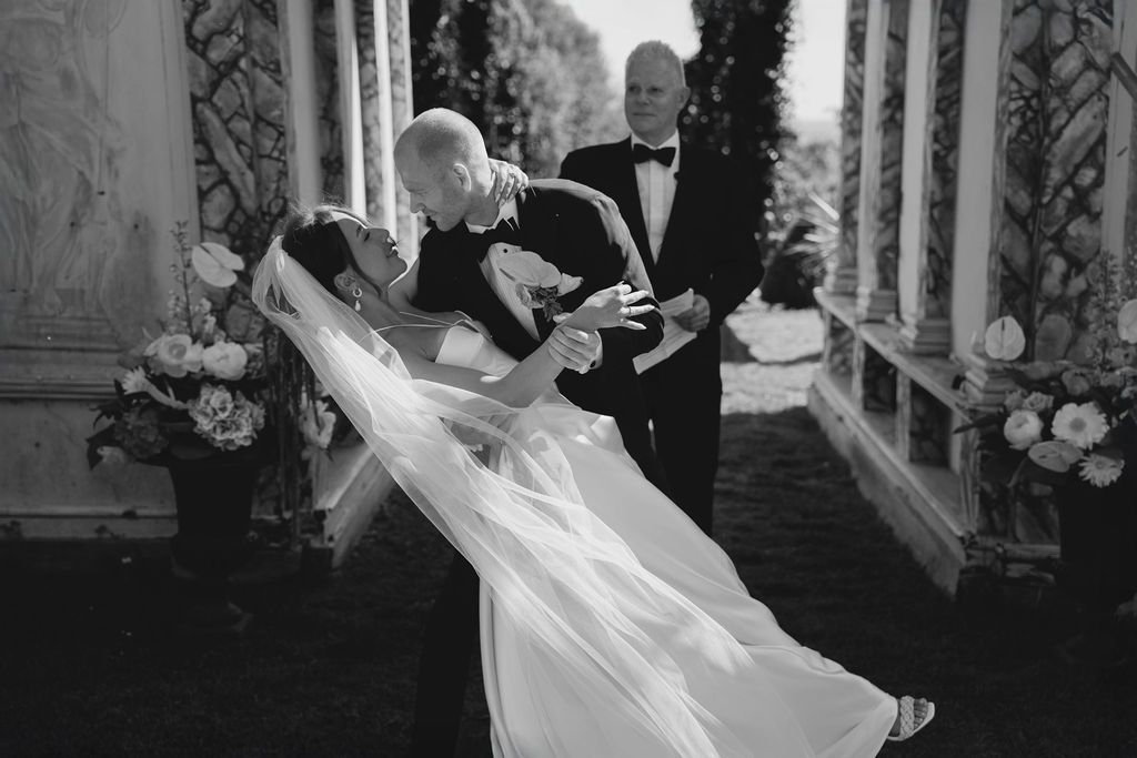 A romantic black and white photo of a couple performing a dramatic dip dance move during their wedding celebration.
