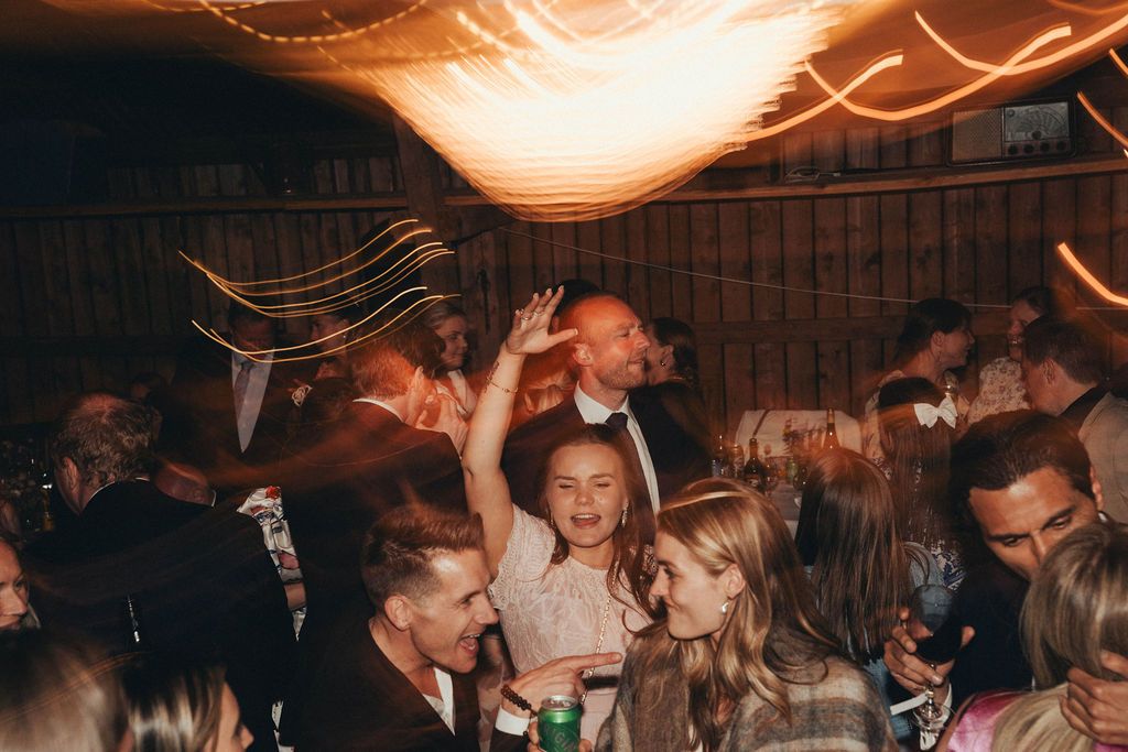 A crowded dance floor at a nightclub with warm orange lighting and people dancing together.