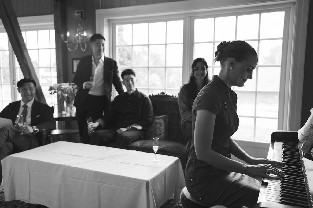 Black and white photo of a reception venue with large windows and guests mingling.