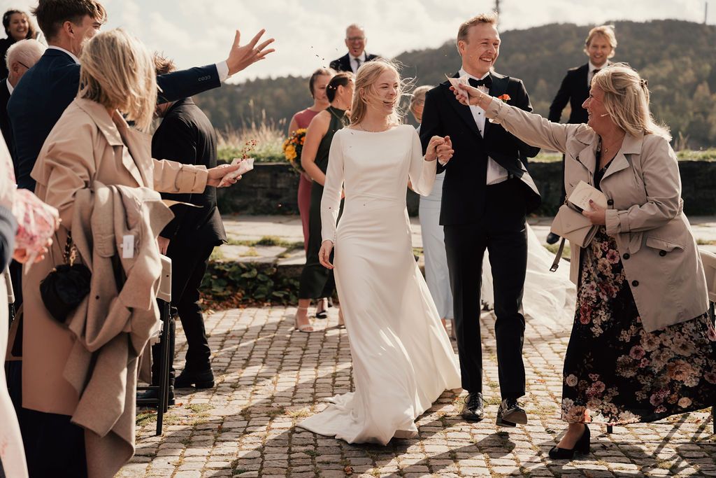 Wedding guests celebrate and dance together during an outdoor reception by the water at sunset.