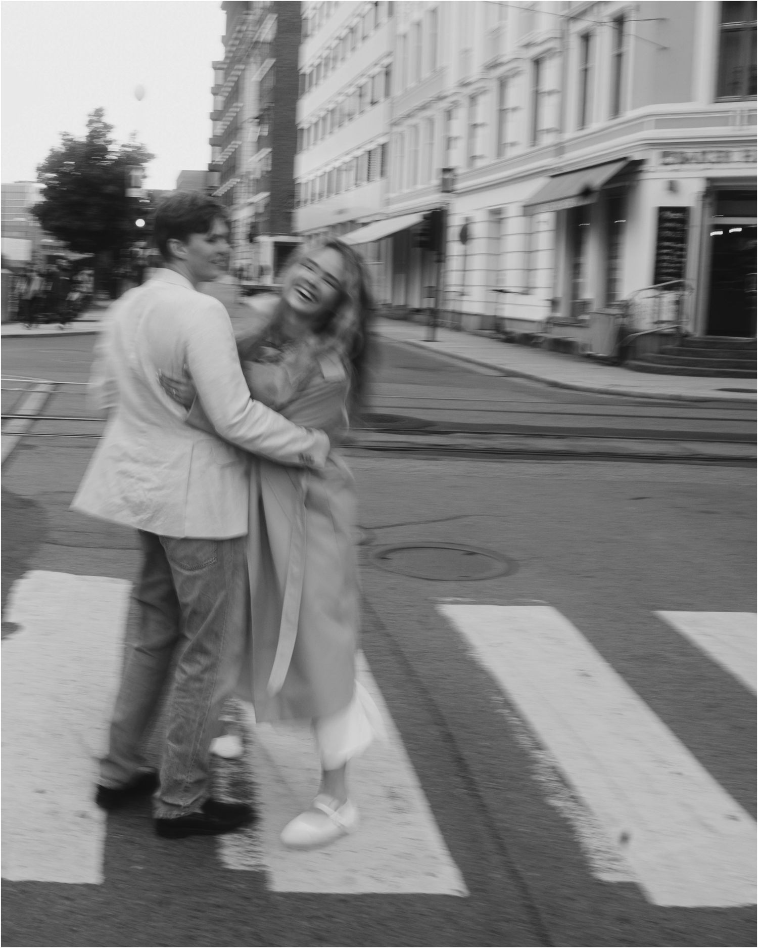 A sequence of black and white photos showing two people playfully interacting on a crosswalk in an urban setting.