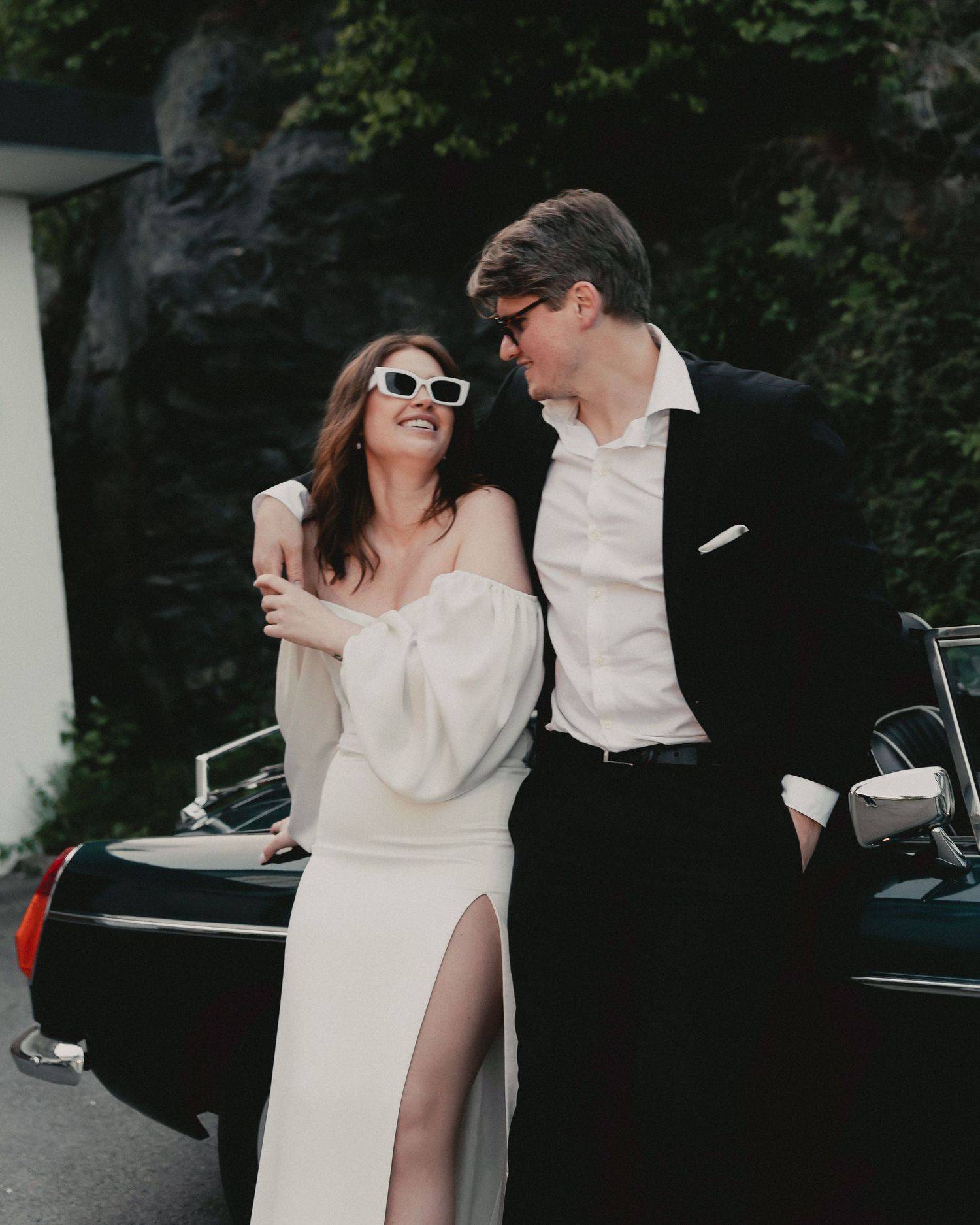 A couple in elegant black and white attire share intimate moments against a dark background in a series of candid shots.