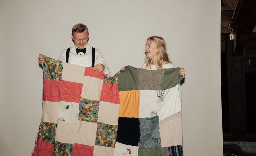 A group of people holding up and displaying various pieces of clothing in a dimly lit room.