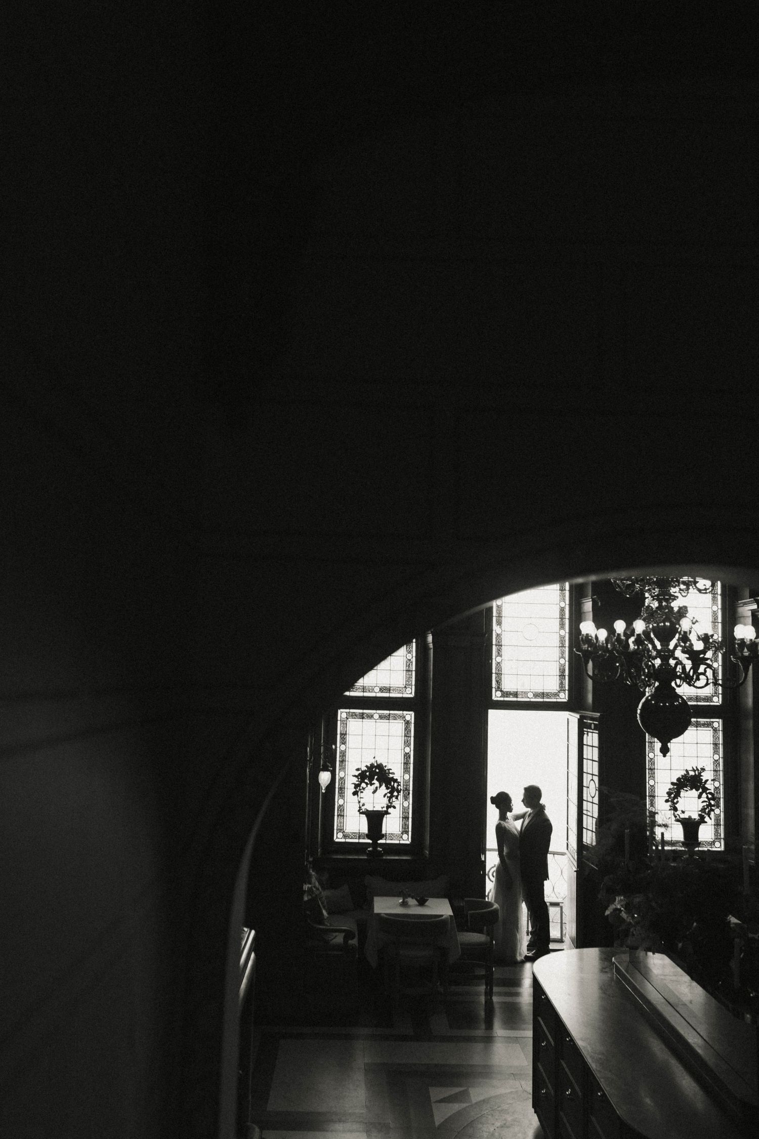 A dark corridor with silhouetted figures against bright windows creates a dramatic contrast in black and white.