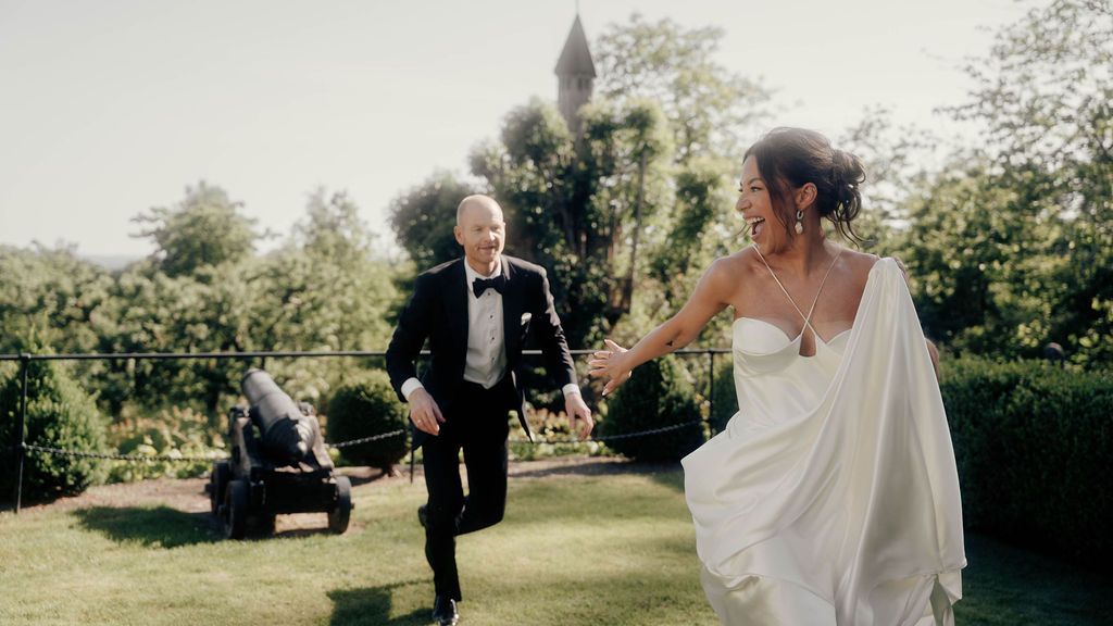 A wedding couple shares a joyful moment together while dancing in a sunlit garden setting.