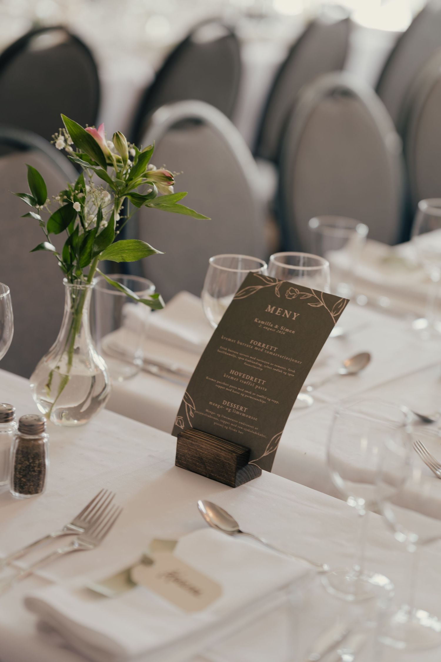 Elegant wedding reception table set with menu card, floral centerpiece, and polished silverware.