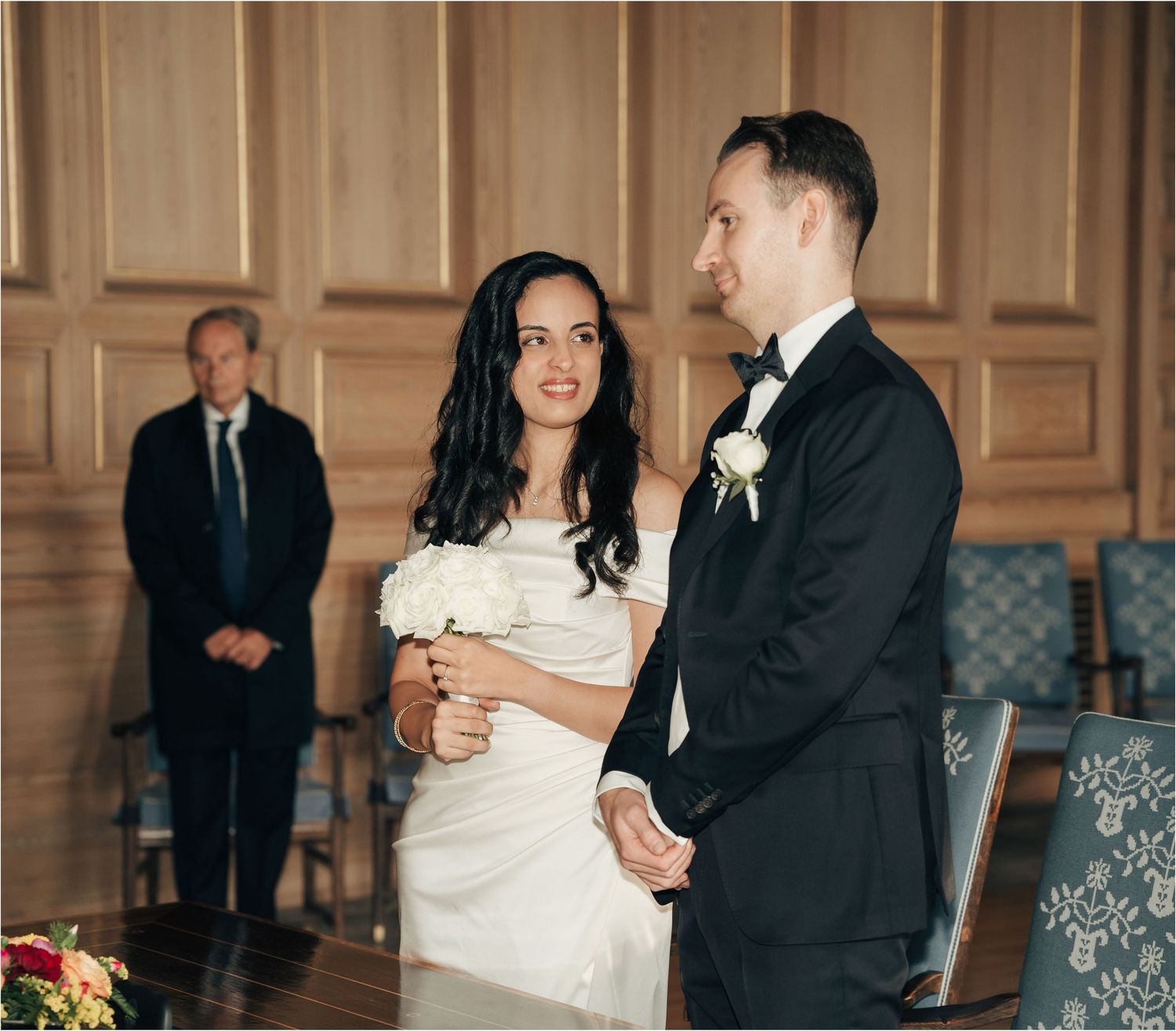 A couple shares their first dance in a grand ballroom with ornate wood paneling during their wedding reception.
