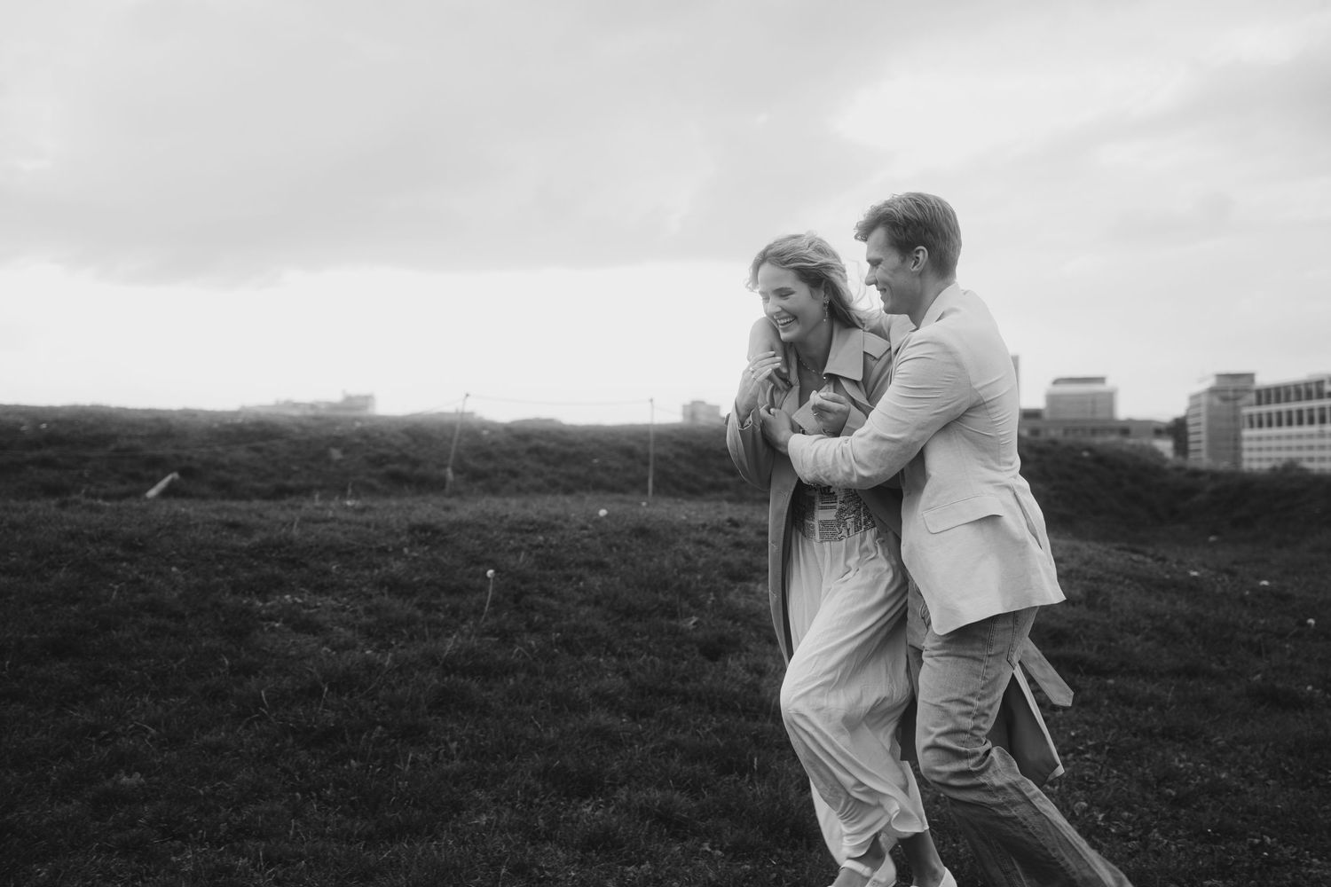 A couple embraces while walking through a misty field in black and white.