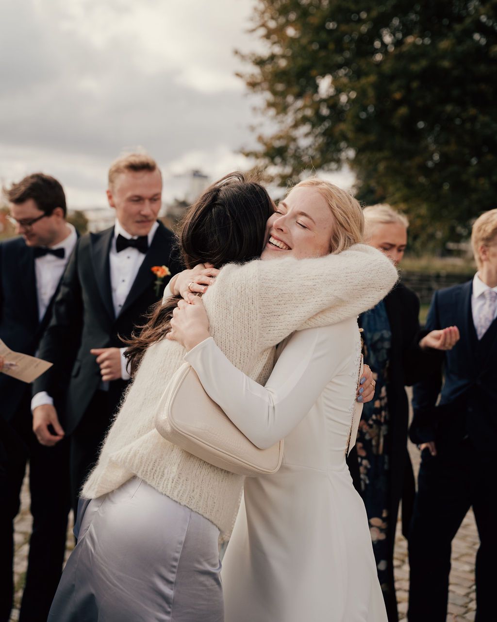 A sequence of four emotional wedding moments showing embraces between people at an outdoor ceremony.