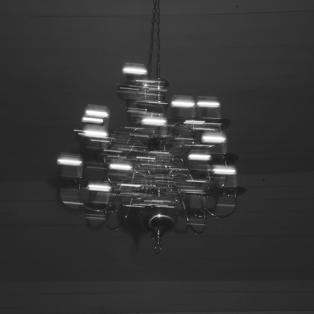 Modern minimalist chandelier with multiple floating light fixtures arranged in an abstract pattern against dark background.