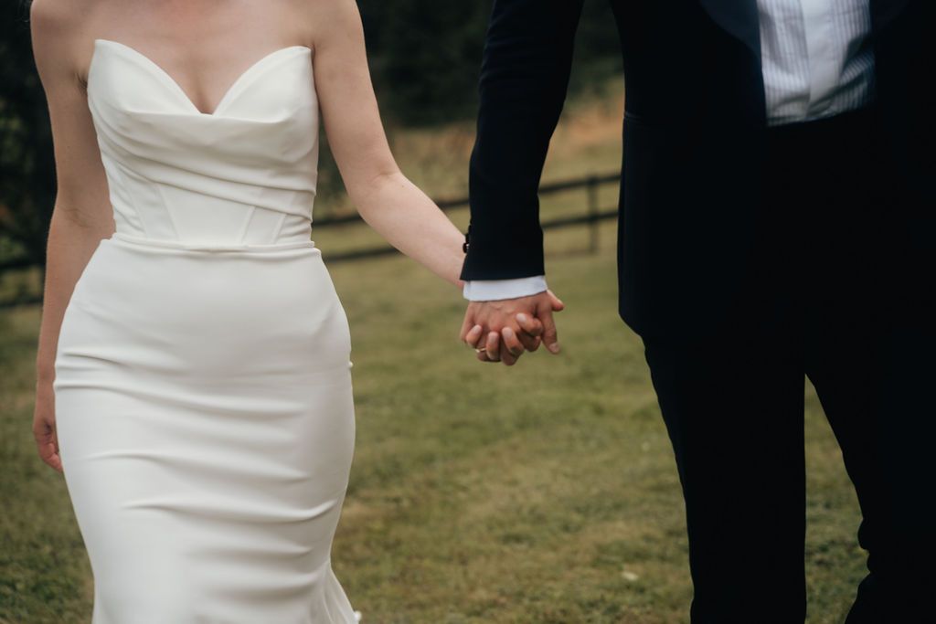 Wedding party members in formal attire walking together on a grassy lawn.
