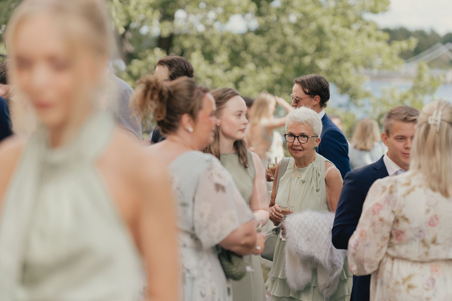 Elegant wedding guests in soft pastel dresses mingling outdoors at a garden wedding reception.