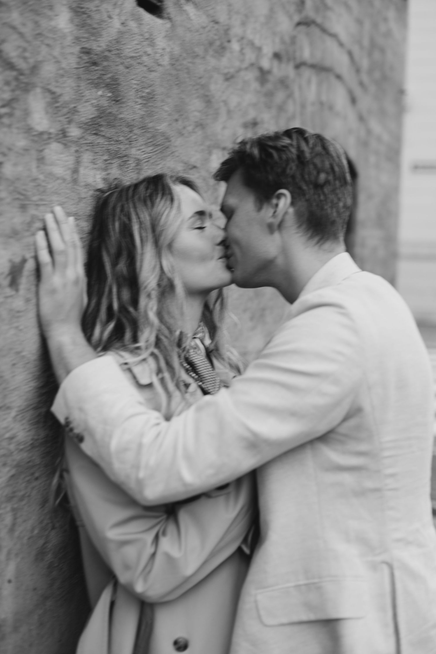 A romantic black and white photo sequence shows a couple sharing an intimate kiss against a textured wall.