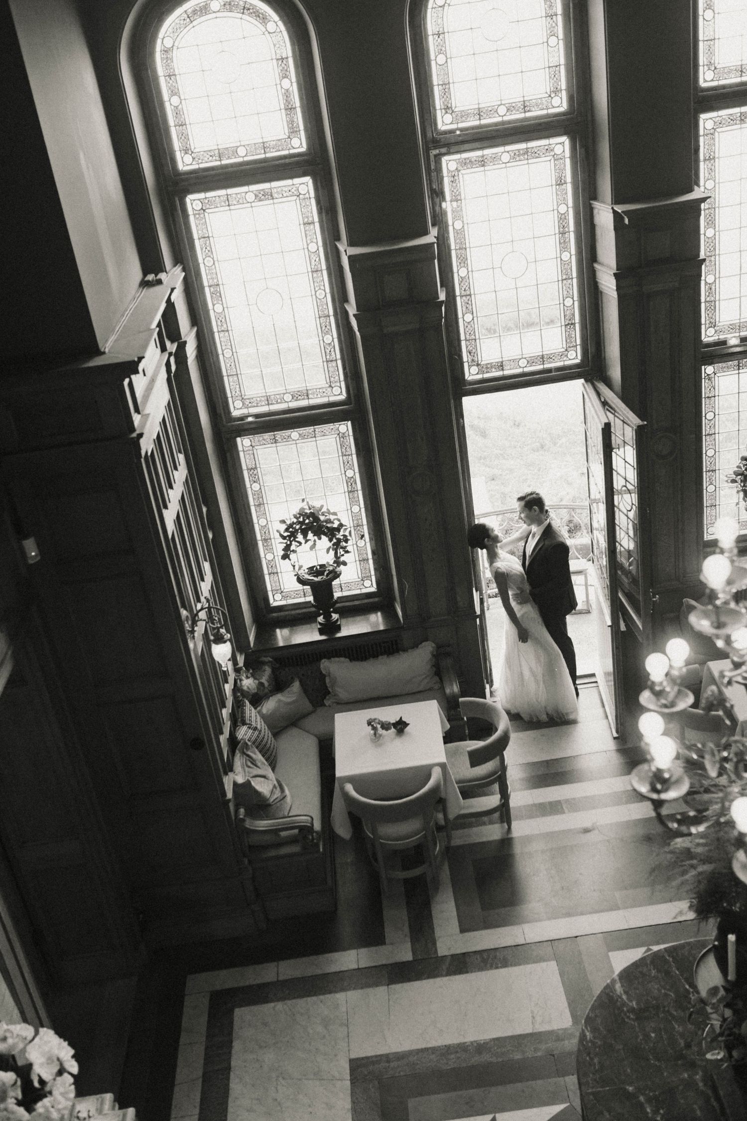 A black and white photo series showing a couple in a church with tall stained glass windows during their wedding ceremony.