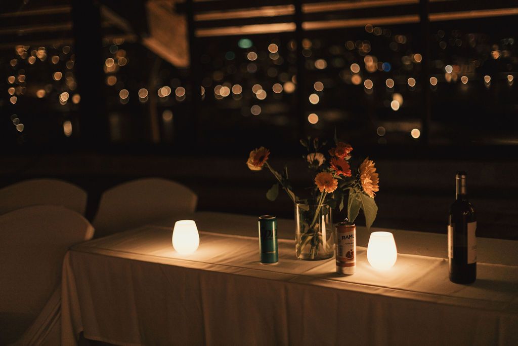 A romantic table setting with glowing lanterns and wine bottles under twinkling lights at night.