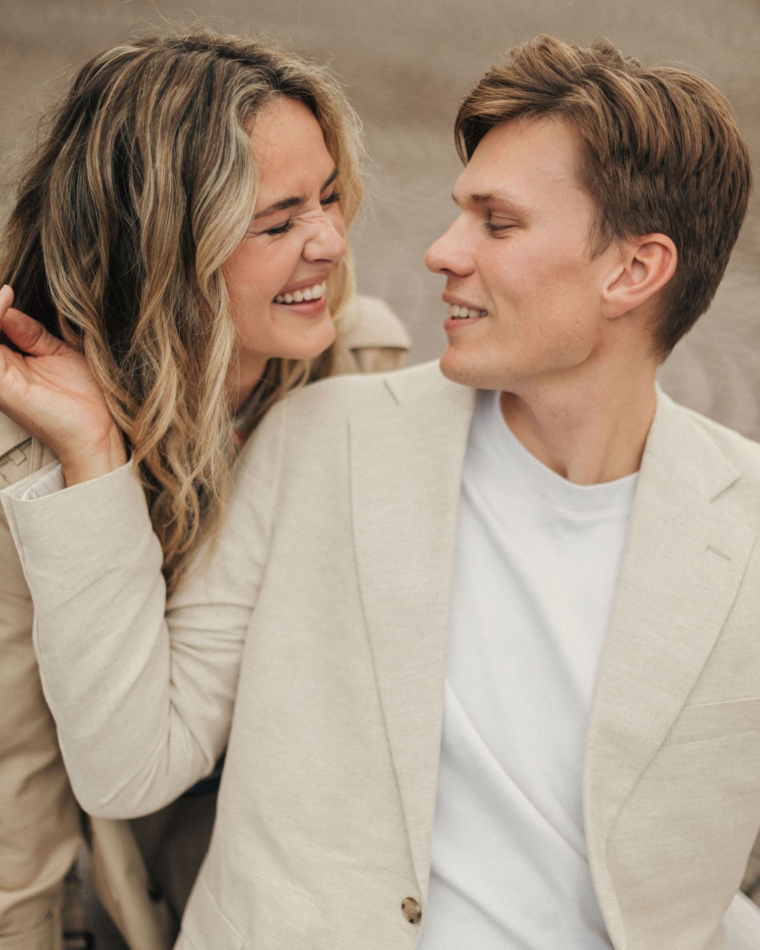 A couple in neutral tones shares intimate moments across a series of candid photos showing laughter and affection.