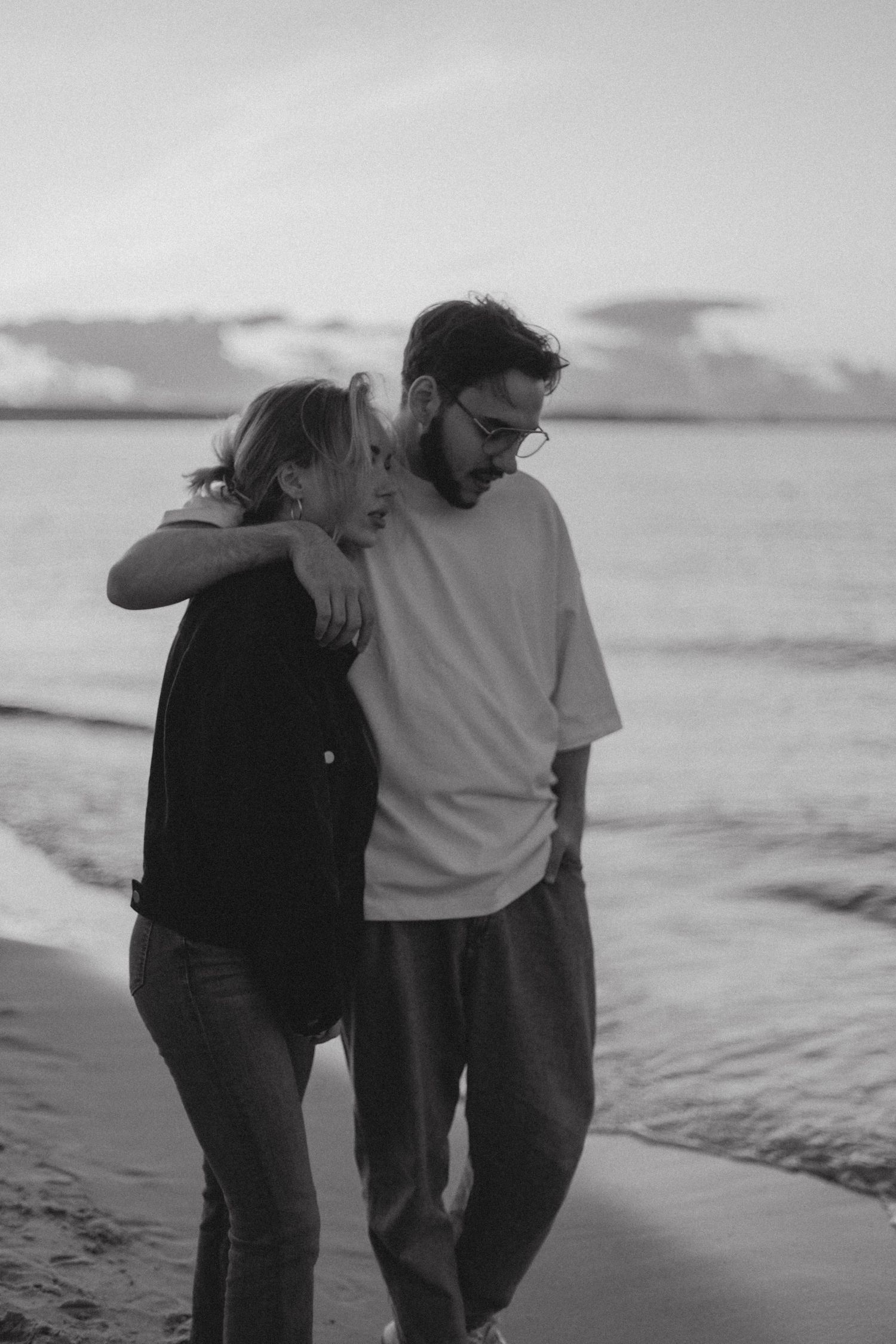 Couple walking together on a misty beach at sunset.